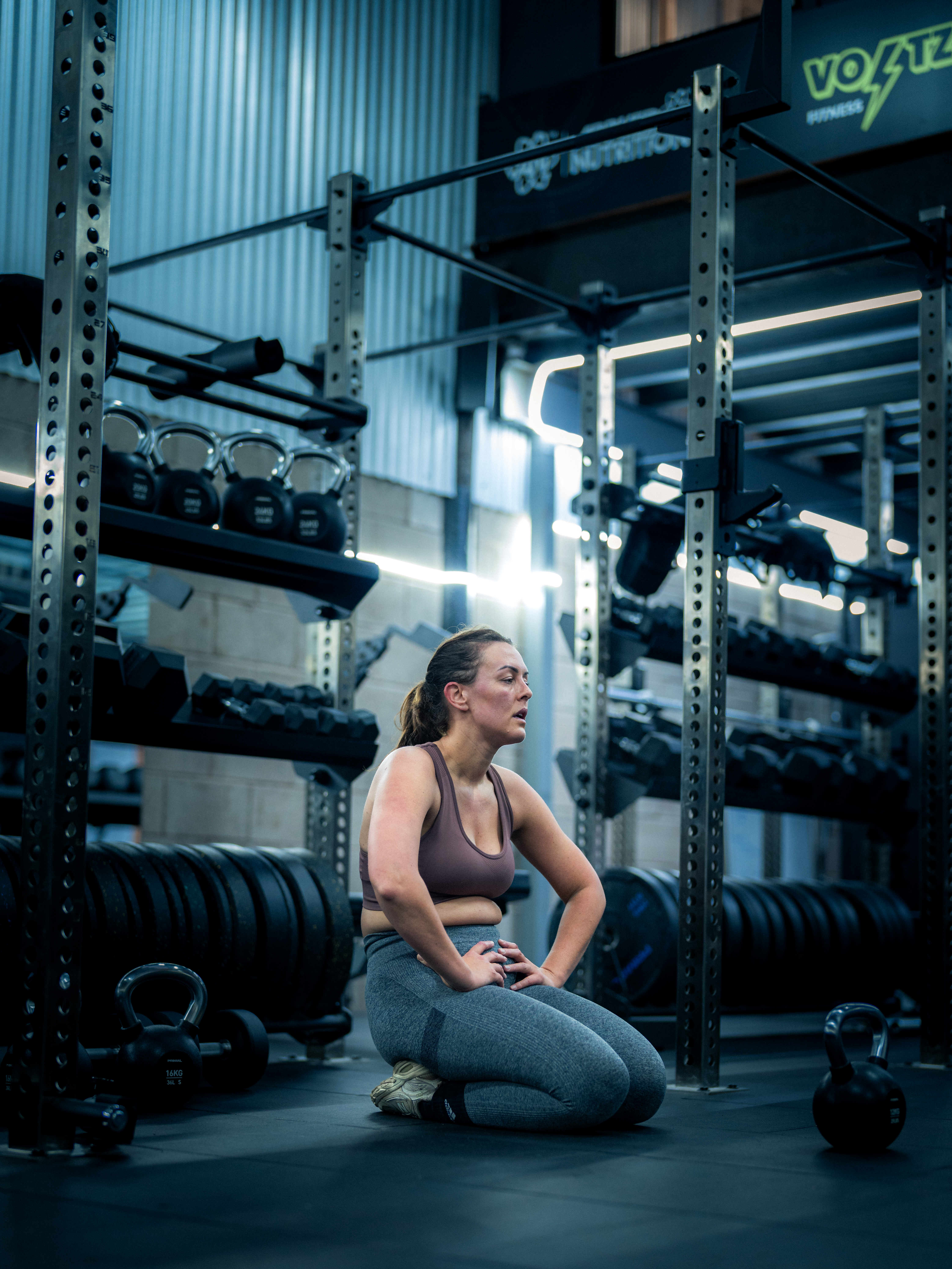 Voltz Fitness member catching breath by kettlebell rack